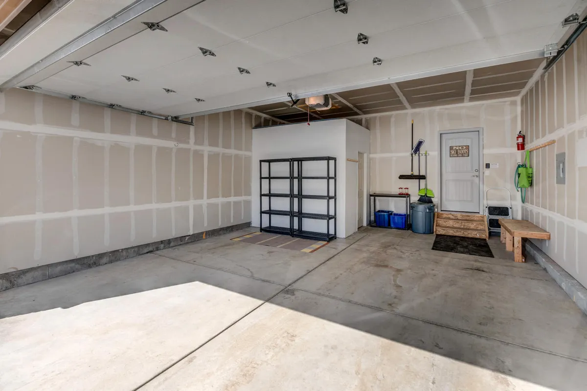 A tidy and functional garage space featuring a shelving unit, a workbench, and a visible door—providing storage for vehicles, gear, and bikes. The organized setup supports easy transitions from outdoor adventure to indoor comfort.