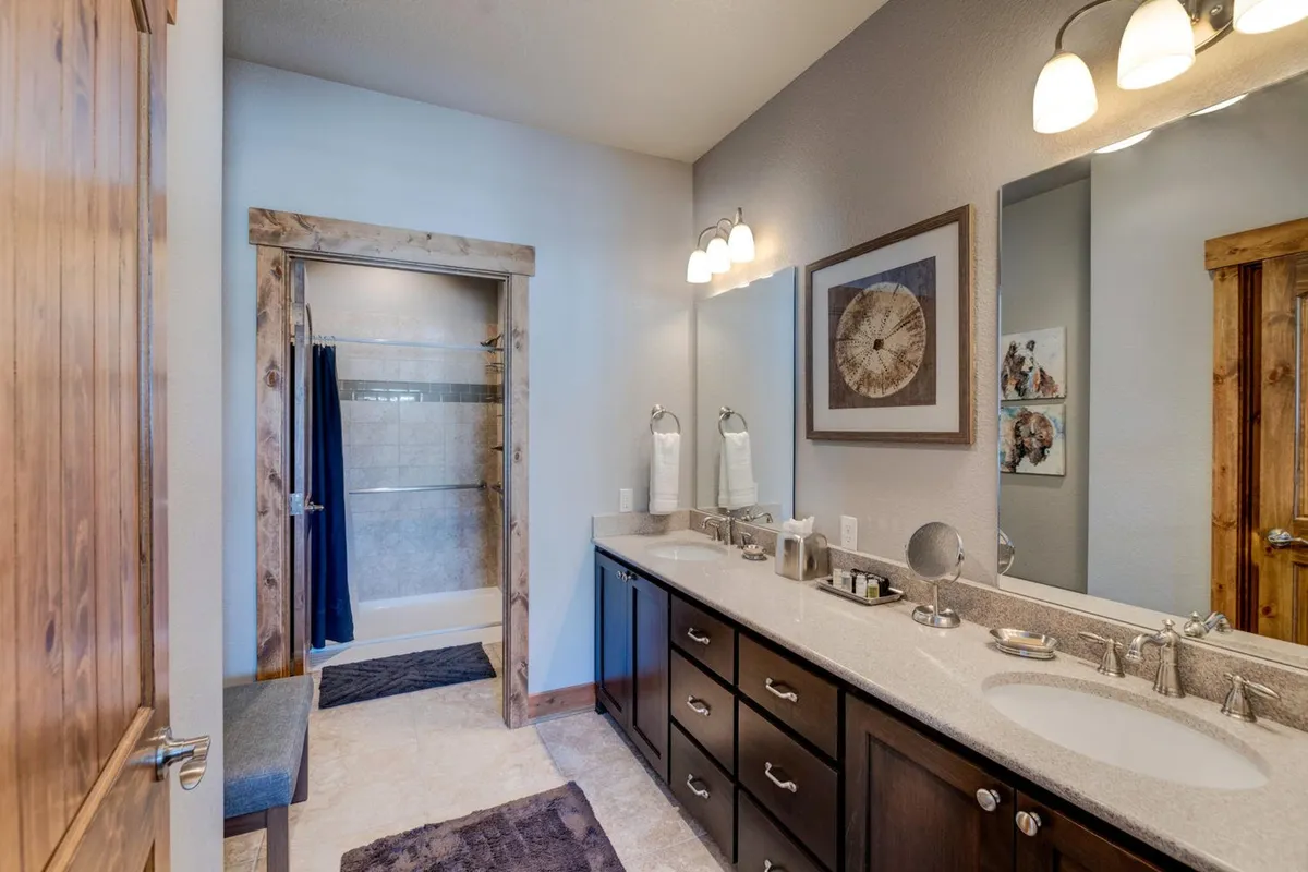 A modern, spa-like bathroom with a double sink vanity, sleek fixtures, a glass-doored shower stall, and calming décor. The space feels organized and luxurious, inviting guests to enjoy relaxing self-care routines.